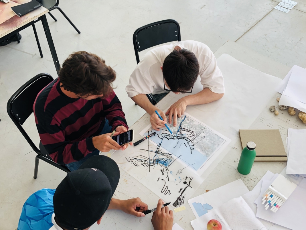 Agrandir l'image - fenêtre modale - Trois étudiants sont assis autour d'une table et travaillent sur projet, la photo est prise d'en haut